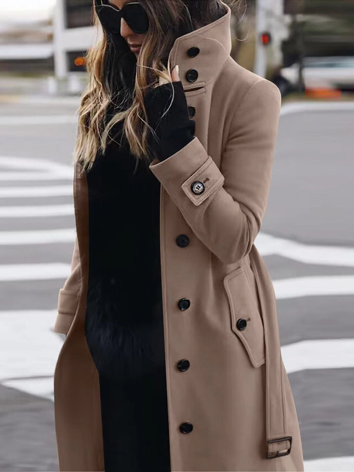 A woman wearing a sophisticated double-breasted coat with a high stand-up collar, perfect for winter fashion.