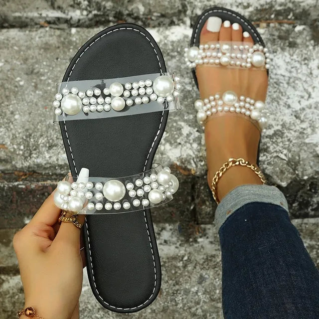 Comfortable women's summer flat sandals featuring stylish pearl straps & clear slides, ideal for warm weather.