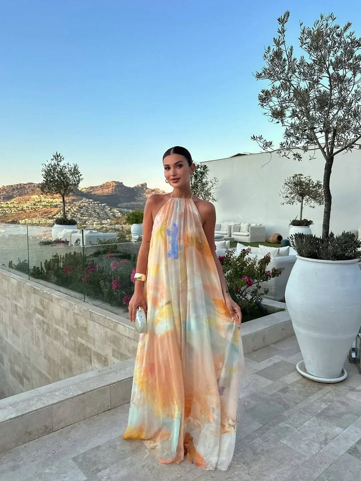 Elegant women's halter neck open back maxi dress with vibrant watercolor print, perfect for summer parties.
