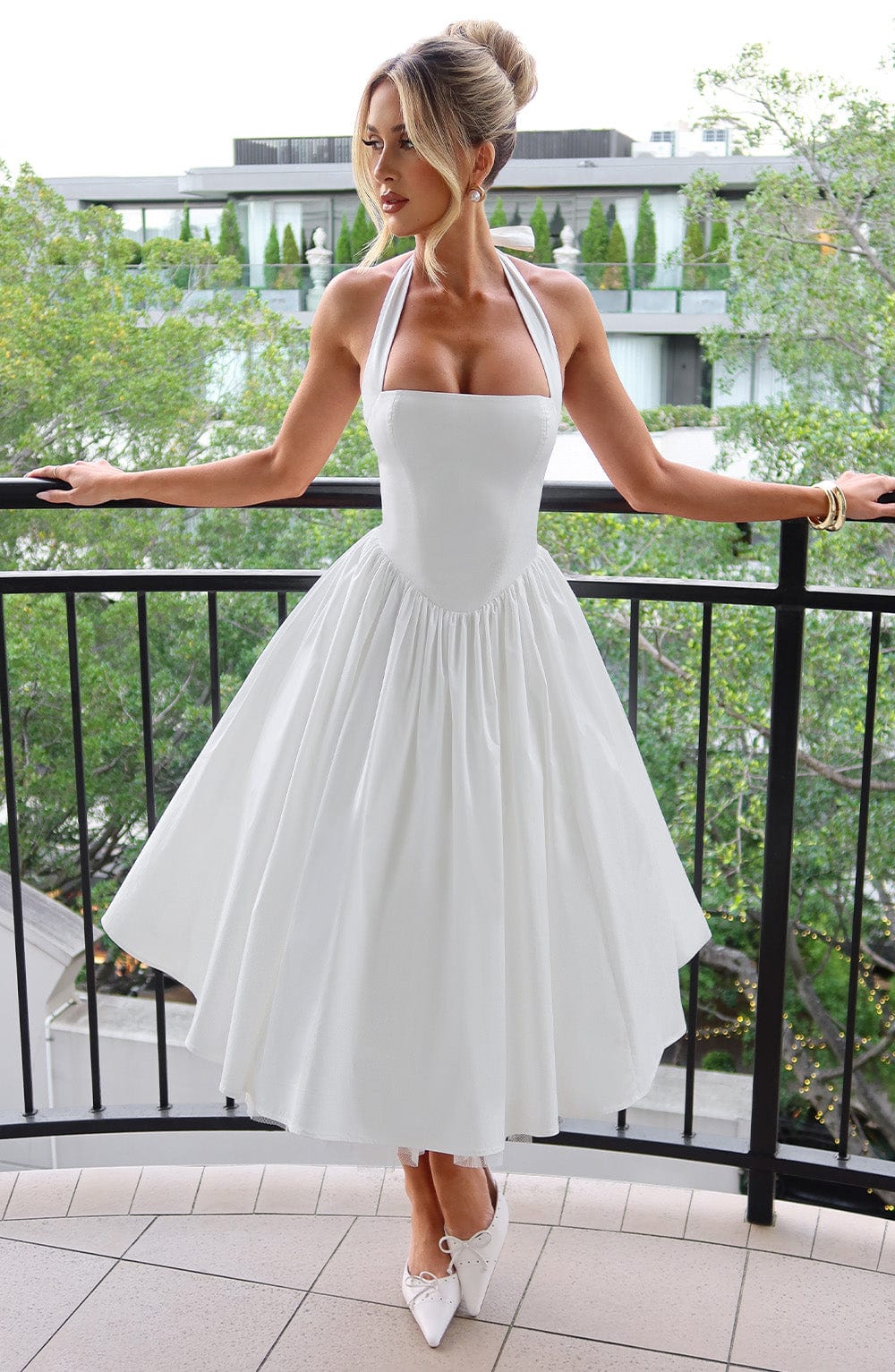 Flowy pleated midi skirt of an elegant women's halter dress, ideal for occasion wear.