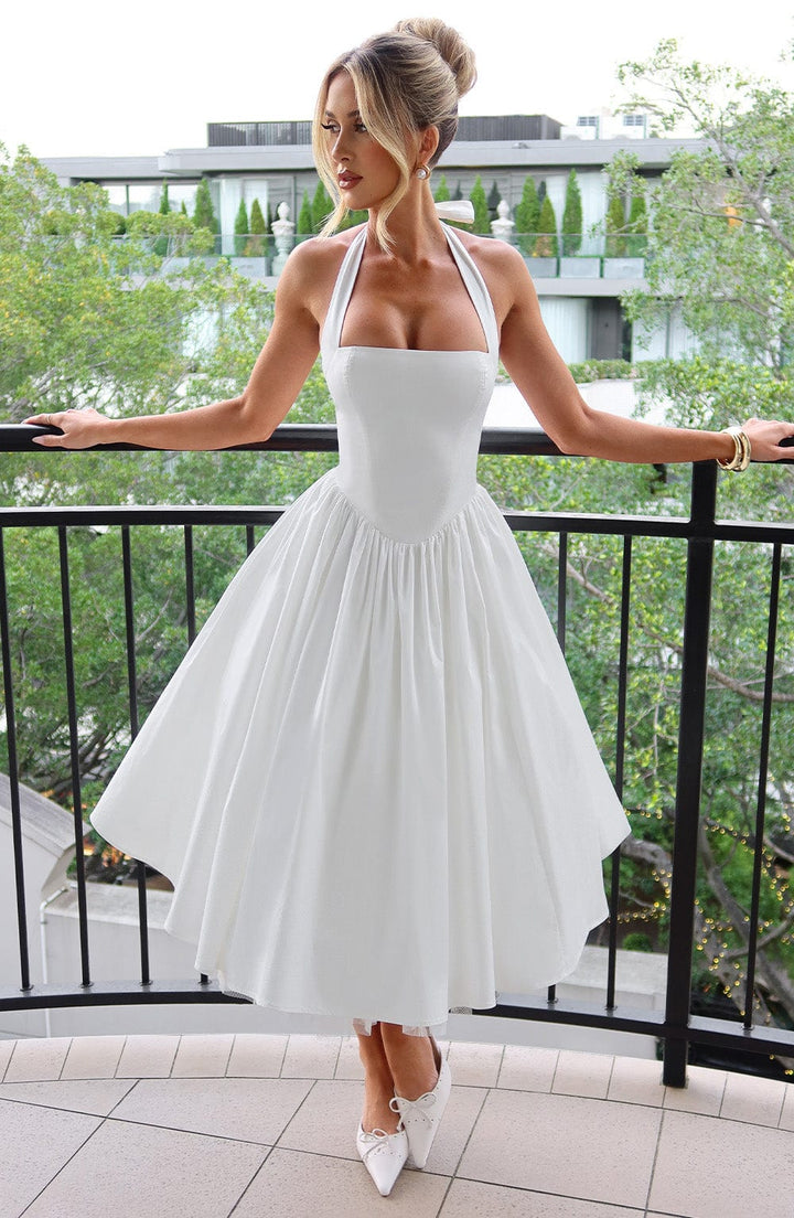 Flowy pleated midi skirt of an elegant women's halter dress, ideal for occasion wear.