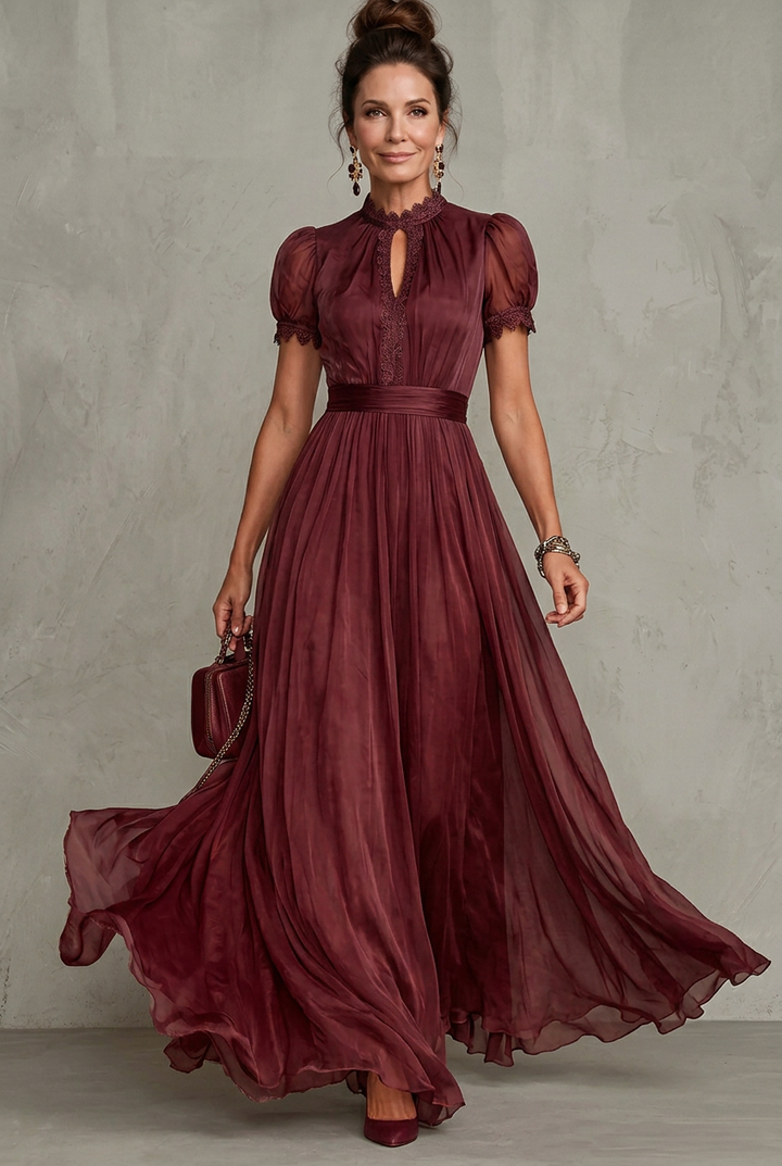 Full shot of a beautiful women's special occasion maxi dress with flattering pleats, lace trim, & puff sleeves.