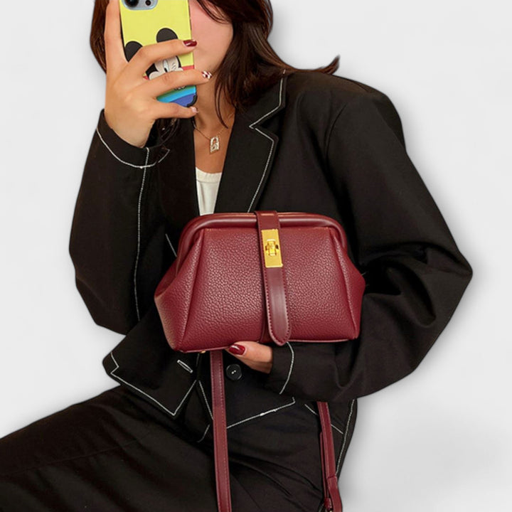Rich brown leather women's shoulder bag, compact and elegant, showcasing its turn lock feature.