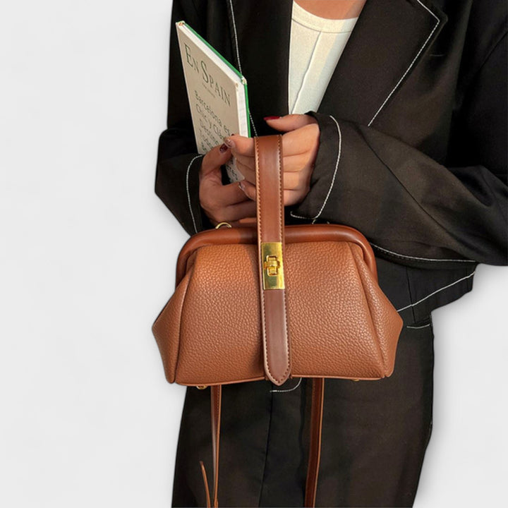 Stylish black leather mini bag for women, featuring a chic gold turn lock and adjustable strap.