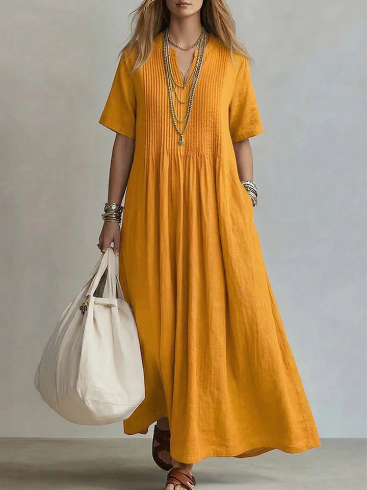 Women's elegant pleated maxi dress with V-neck. Relaxed fit, flowy design, and pockets for comfortable summer fashion.