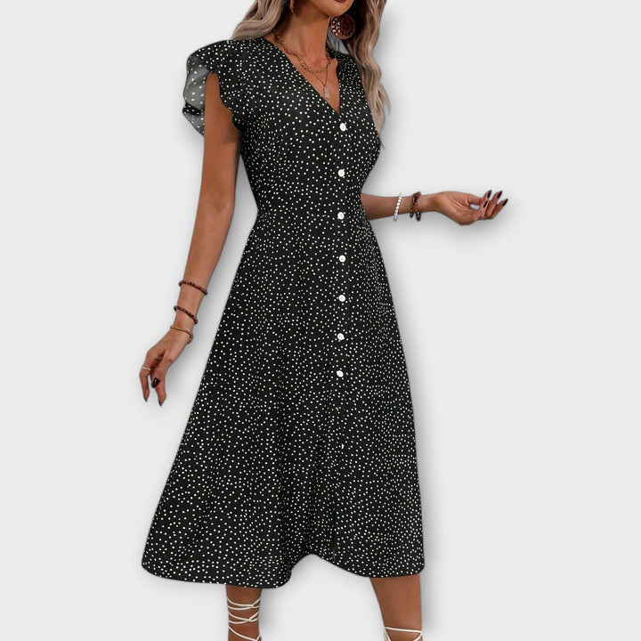 Woman in elegant polka dot A-line midi dress, comfortable for movement, great for summer parties.