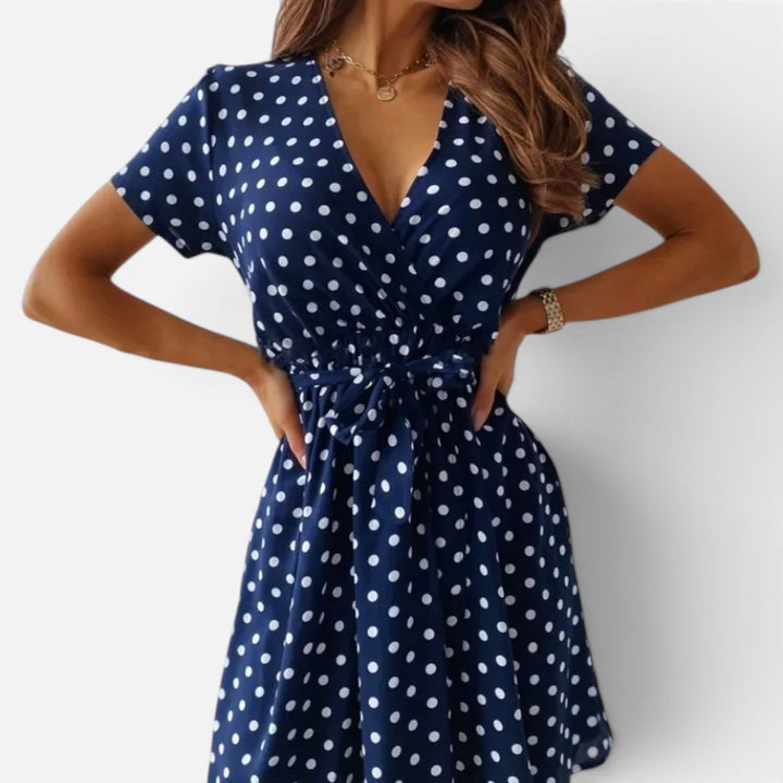 Flowy short sleeve women's mini wrap dress featuring a classic polka dot pattern. Casual & elegant.