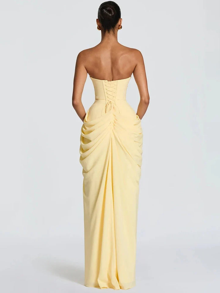 Close-up of a women's elegant strapless maxi dress with intricate ruching and a dramatic high slit detail.