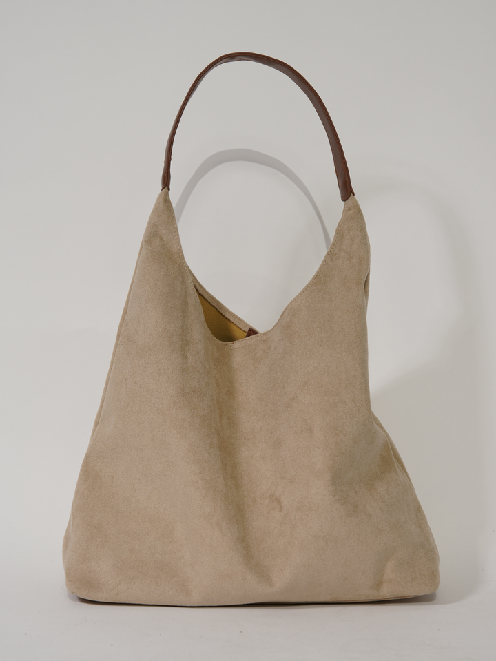 Detail of elegant clasp & sturdy handles on versatile suede tote bag. Stylish women's fashion accessory.