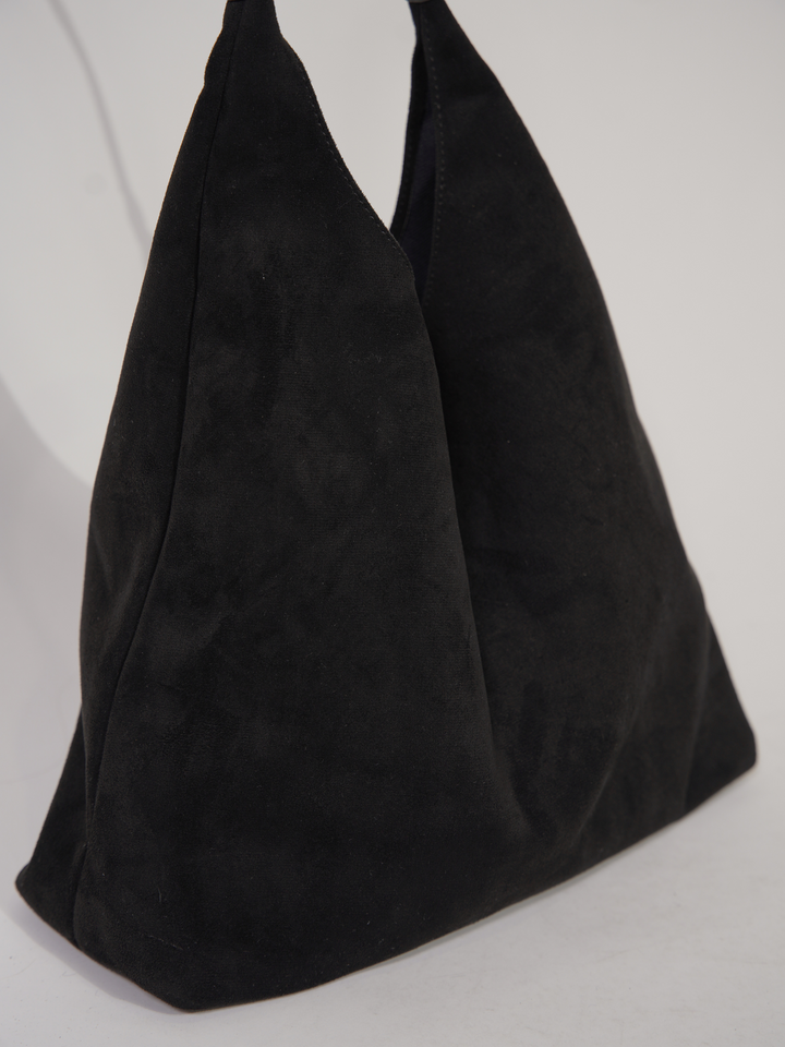 Woman carrying elegant suede tote bag on shoulder. Versatile everyday fashion accessory for women.