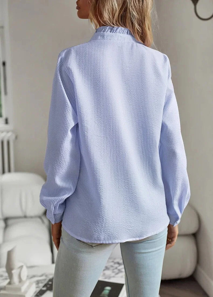 Chic women's blouse featuring a ruffled collar, subtle texture, & stylish stripes. Ideal elegant top.