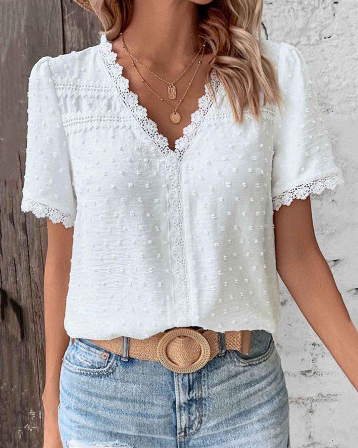 Relaxed fit short sleeve women's blouse featuring a flattering V-neck, intricate lace, and textured Swiss dots.