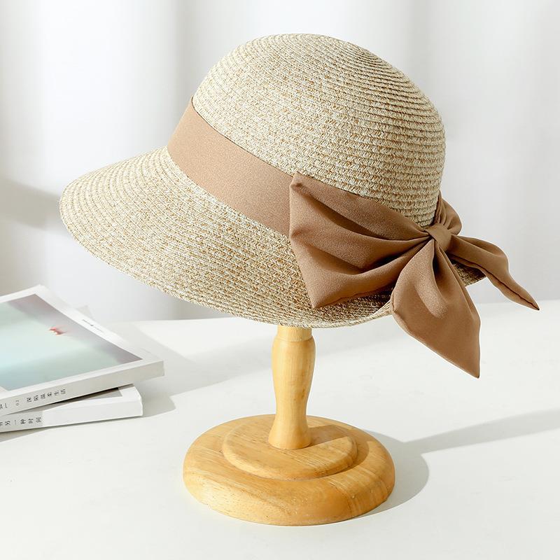 Elegant women's wide brim straw sun hat with bow, perfect for summer beach style and sun protection.