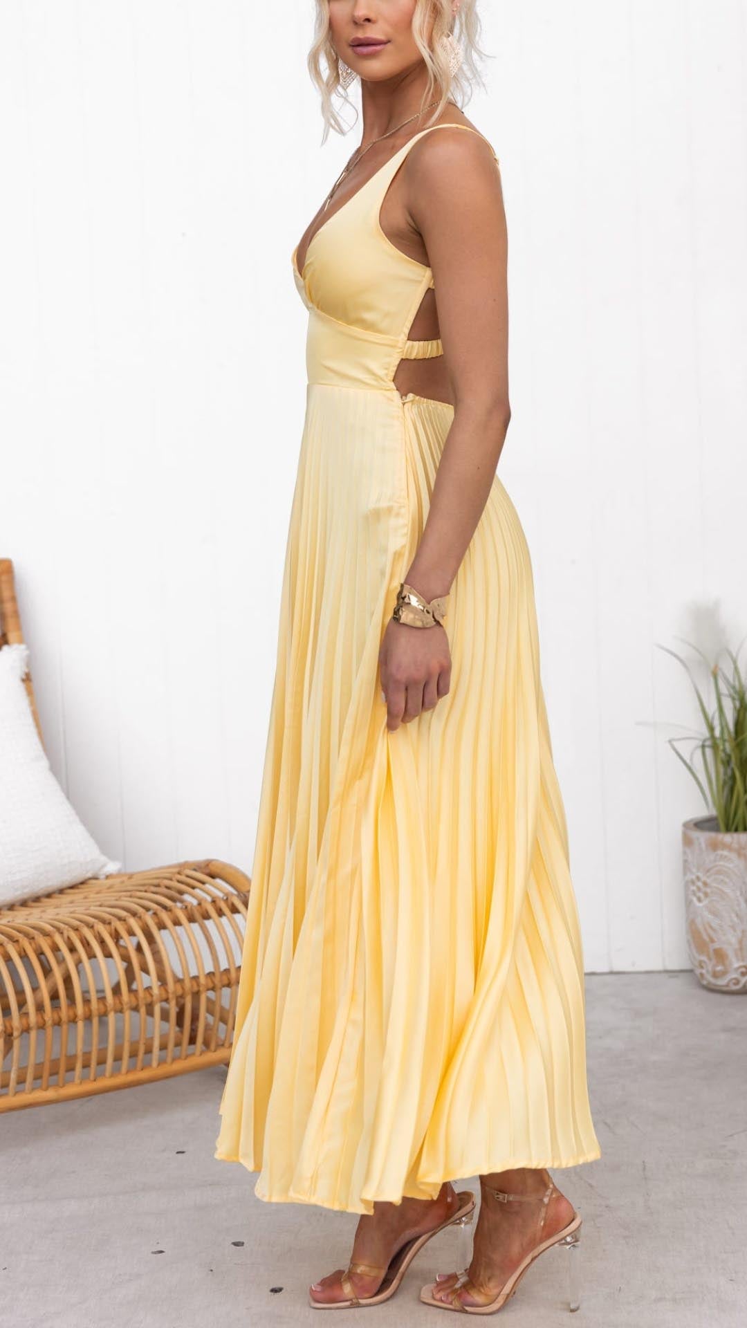 Sleeveless yellow V-neck maxi dress for women, featuring elegant pleats, an open back, and A-line silhouette.