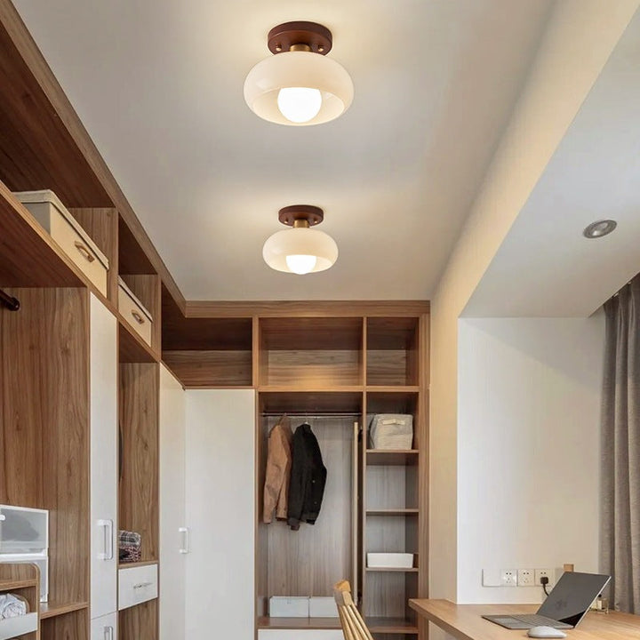 Warm atmospheric lighting from a French Bauhaus style flush mount ceiling lamp with elegant wood trim.
