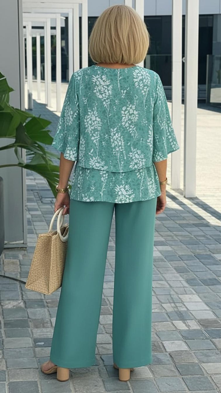 Full view of a woman wearing a fresh teal floral two-piece outfit, showcasing the flowy top & wide-leg pants.