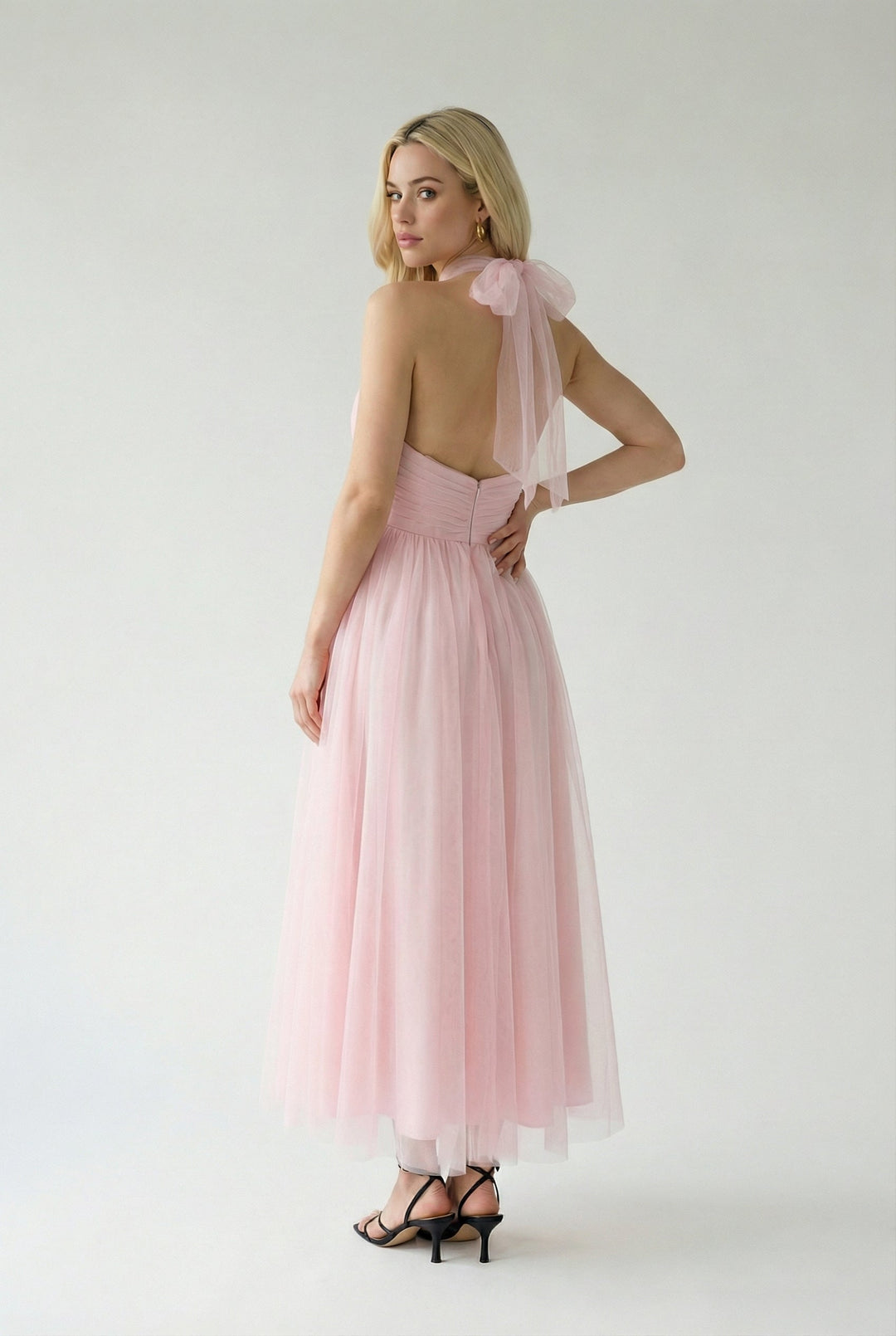 Women's feminine blush pink halter midi dress, ideal as a wedding guest or party outfit.