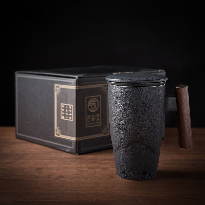 Elegant handmade ceramic tea mug with infuser for loose tea, featuring a rustic wooden handle.