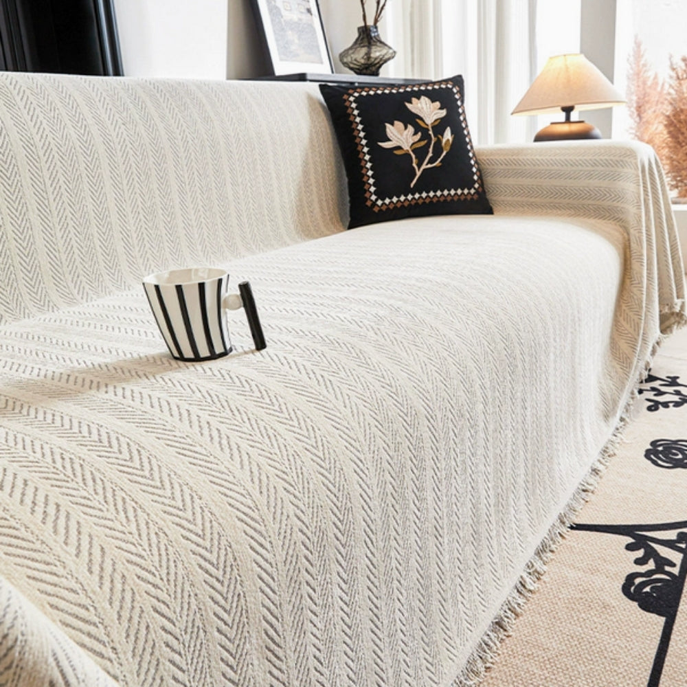 Elegant herringbone chenille sofa cover with tassels. Machine washable and pet friendly, this anti-slip throw protects furniture in style.