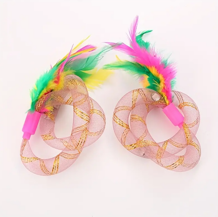 Happy cat pouncing on an interactive feather shuttlecock and mesh ring toy, promoting playful exercise.
