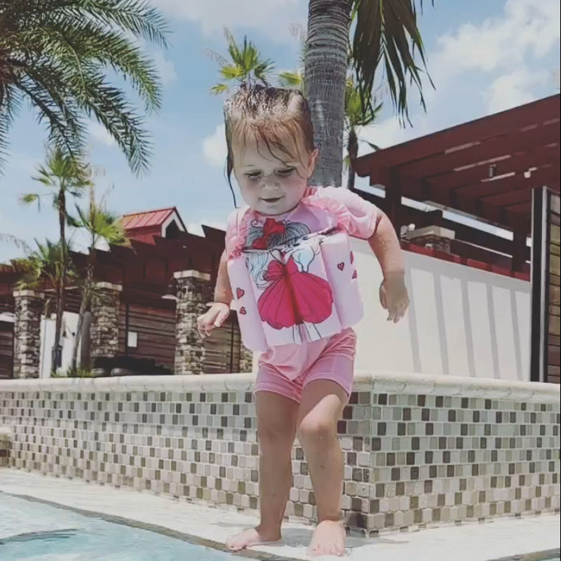 Full body shot of a child in a green buoyancy vest, ready for the pool.
