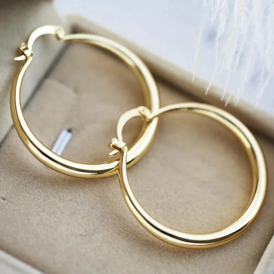 Large gold hoop earrings for women, elegant and timeless everyday jewelry with a secure snap closure. Fashion accessory.