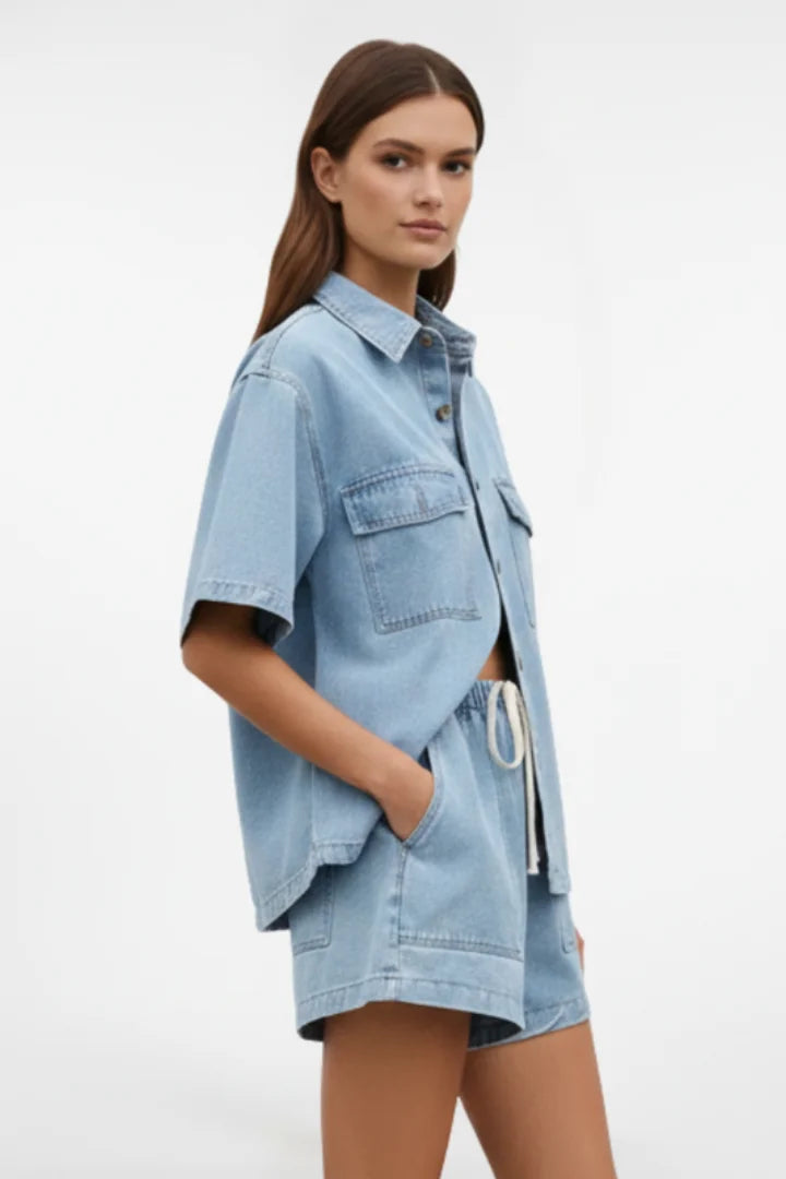 Women's light blue denim matching collared short-sleeve top & high-waisted shorts. Stylish two-piece summer set.