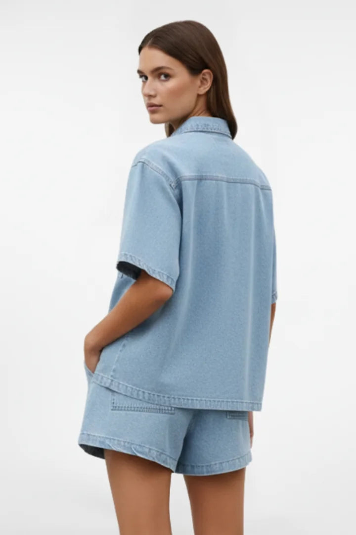 Trendy women's light blue denim collared short set. Chic two-piece summer fashion with short-sleeve shirt & shorts.