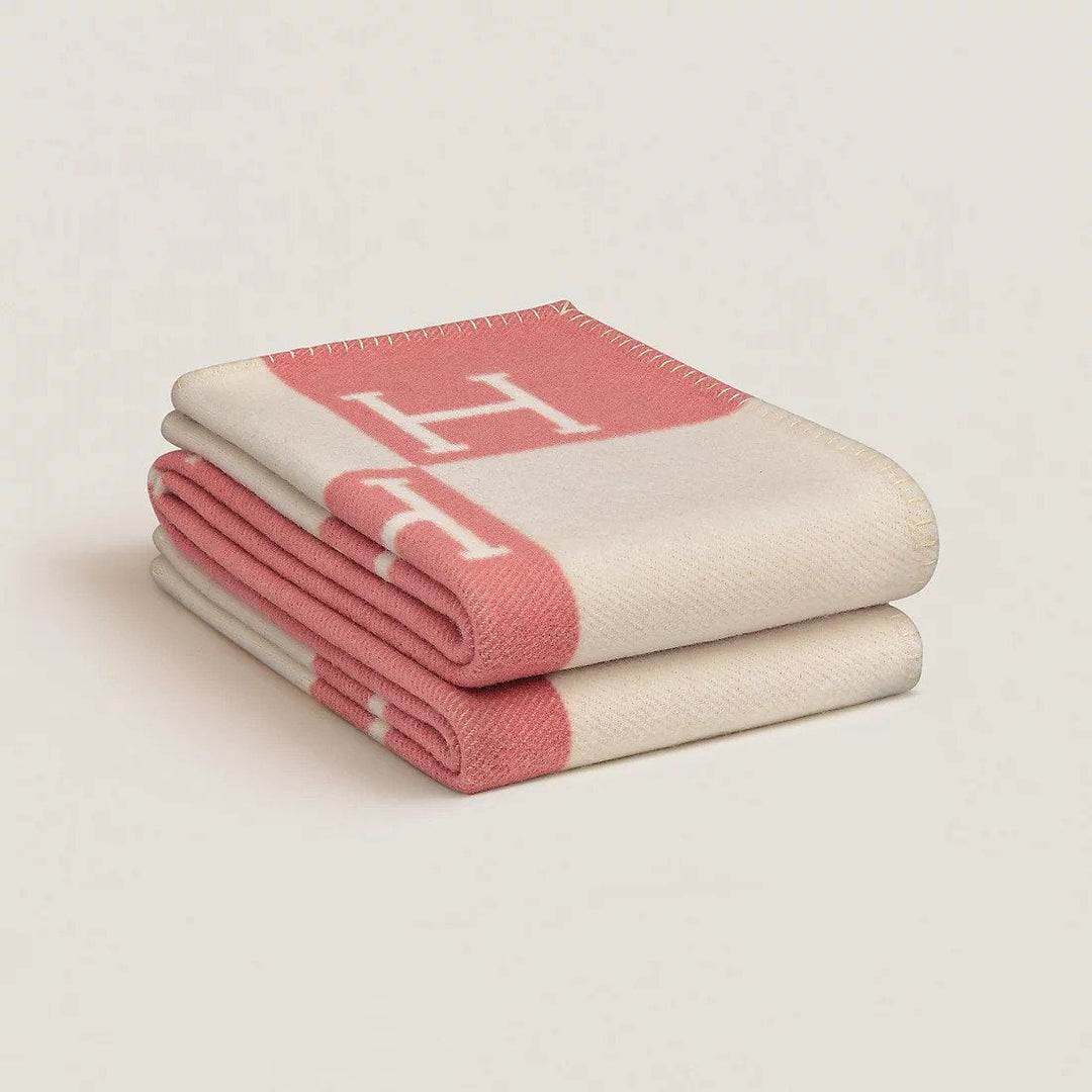 A hand holding the corner of a soft navy blue wool cashmere throw blanket, highlighting its luxurious feel