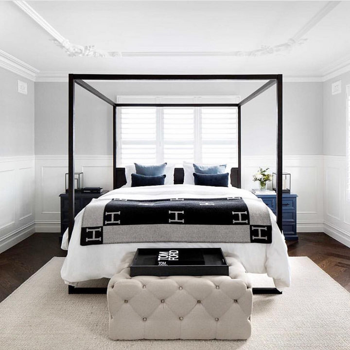 Spacious shot of a light grey wool cashmere throw blanket folded neatly on a bed, perfect for warm nights