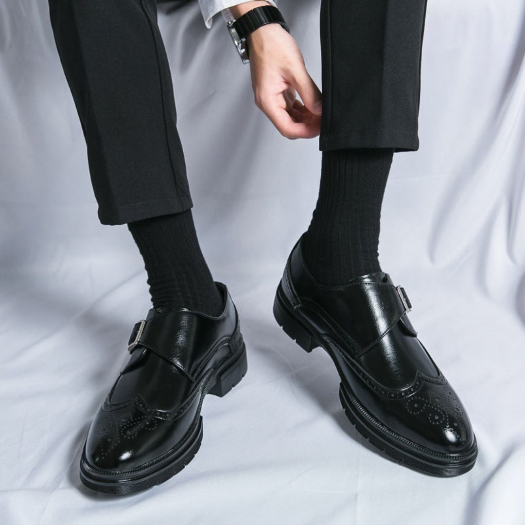 Close-up of men's brown leather wingtip brogue detail on monk strap dress shoes.