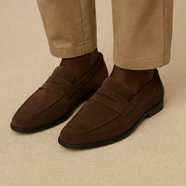 Close-up of men's brown suede penny loafers, showcasing stitching and easy slip-on design.