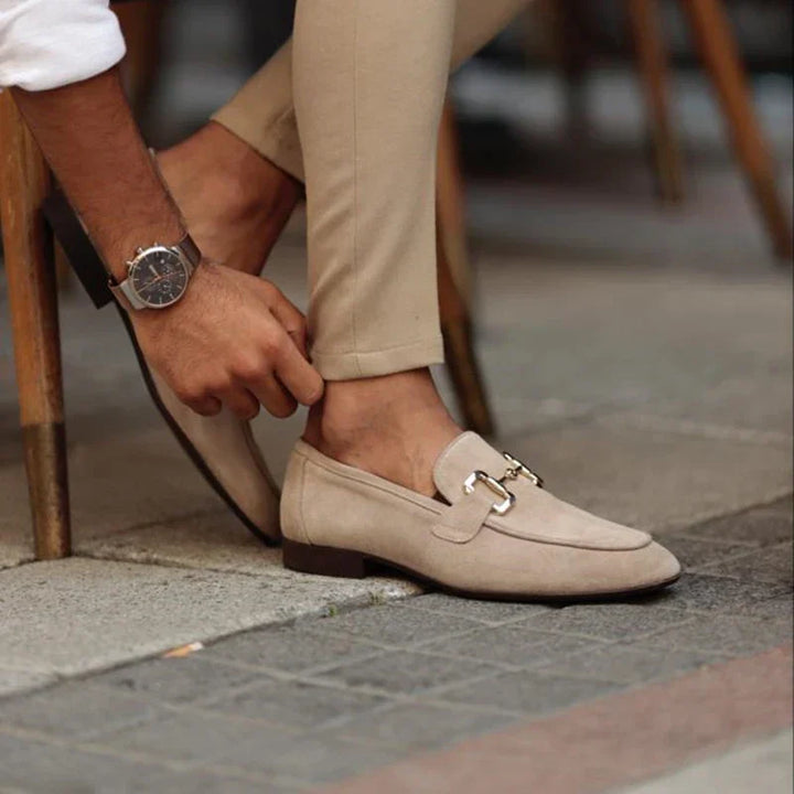 Men's black slip-on loafers with elegant metal buckle, perfect for smart-casual wear.