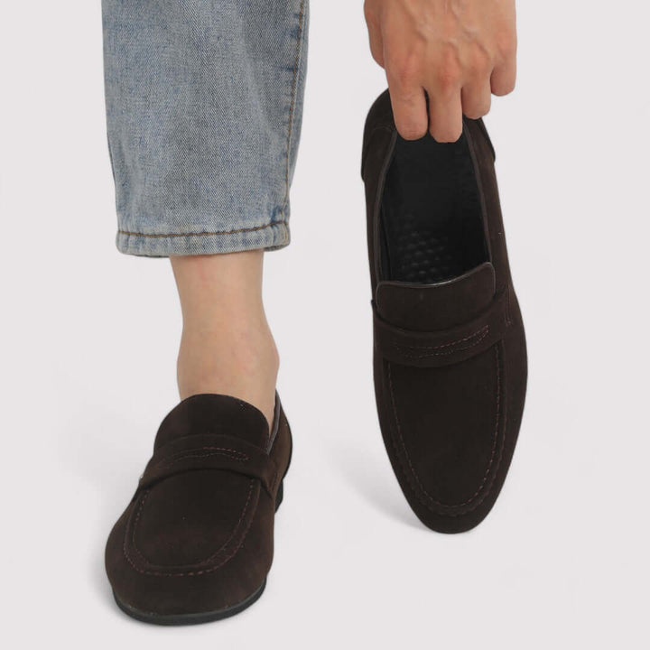 Close-up of the iconic penny slot detail on men's classic brown leather loafers. Stylish & timeless men's footwear.