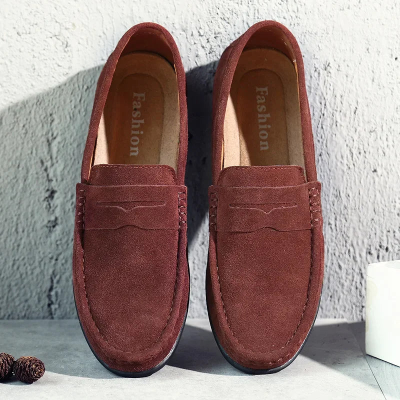 Close-up of men's tan suede loafers featuring a traditional penny strap detail.