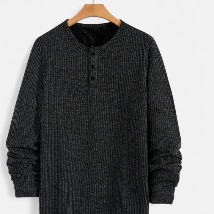 Close-up of men's cable-knit henley sweater, showcasing texture & button placket. Classic regular fit knitwear.