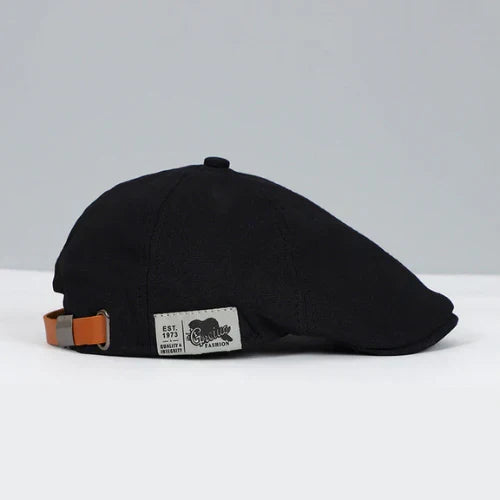 Close-up of a men's buckled ivy cap, showcasing the detailed paneling and button on top. Classic flat cap.