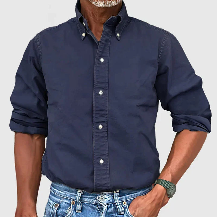 Man in a formal setting wearing a classic long-sleeve button-up shirt, an essential men's wardrobe staple.