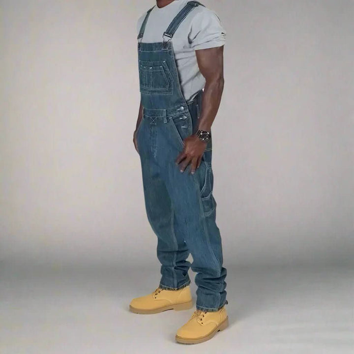 Casual and streetwear-inspired men's dark wash denim overalls with utility pockets.