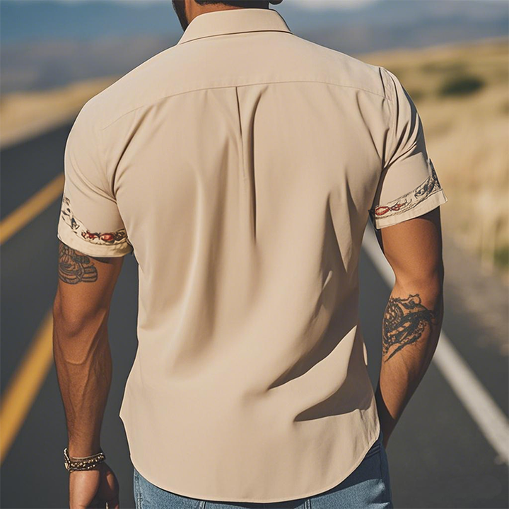 Close-up of men's designer quality short sleeve shirt, showcasing elegant floral embroidery and unique style.