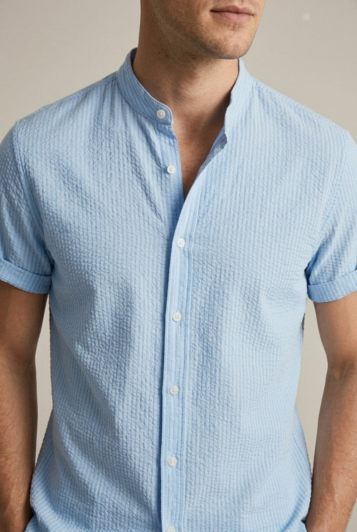 Textured seersucker short sleeve men's shirt, loose fit, band collar. Ideal light blue summer casual wear.