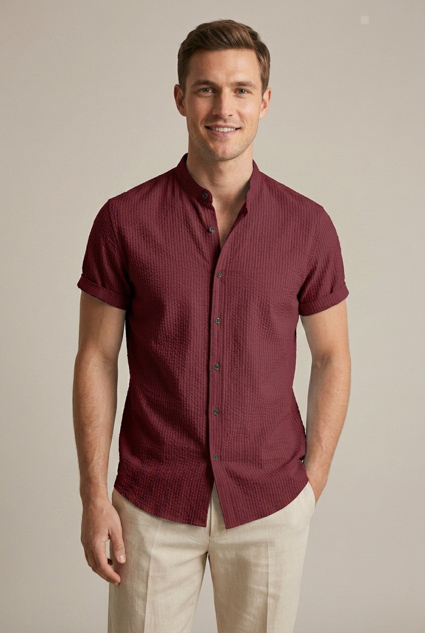 Man casually dressed in a light blue seersucker short sleeve summer shirt with a distinct band collar.