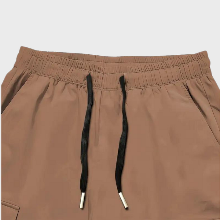 Close-up of men's brown cargo trousers showing pocket detail and relaxed fit.