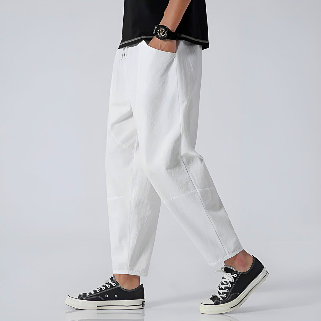 Man in relaxed fit cropped chinos, sitting comfortably, highlighting freedom of movement and casual summer style.