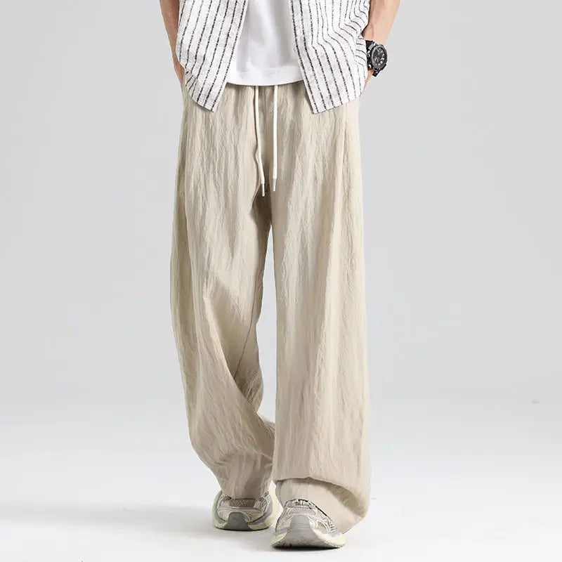 Close-up of men's relaxed fit linen wide leg trousers showing drawstring waist and natural fabric texture.