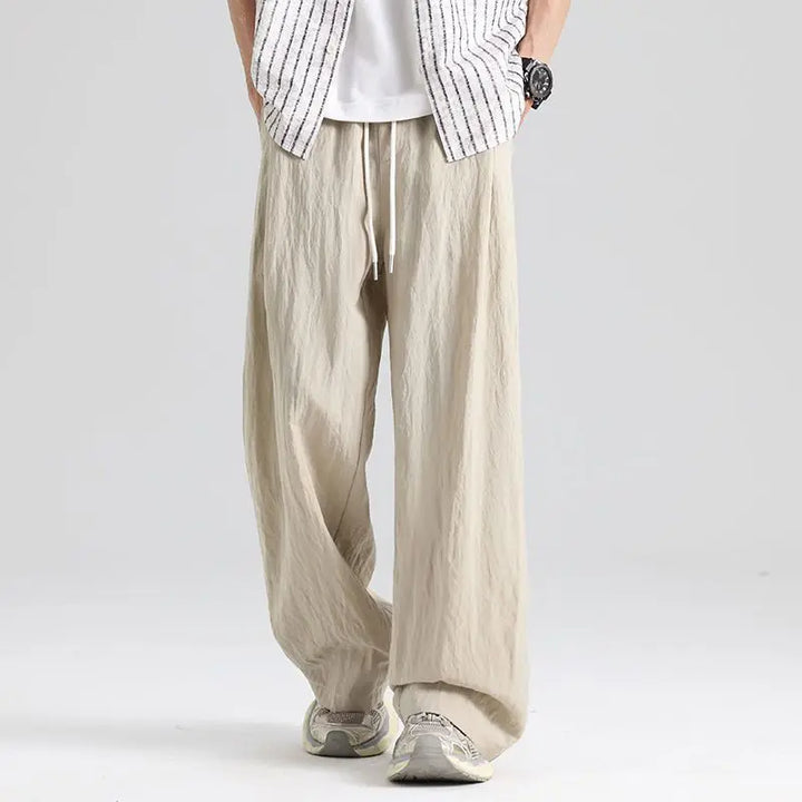 Close-up of men's relaxed fit linen wide leg trousers showing drawstring waist and natural fabric texture.