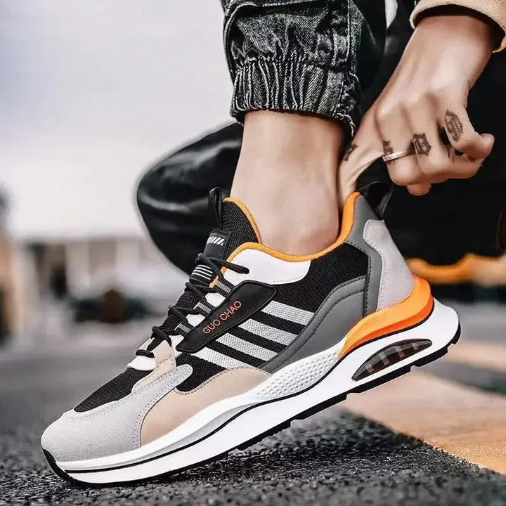 Close-up: Men's beige, green & orange retro sporty sneakers. Vintage design with cushioned comfort.
