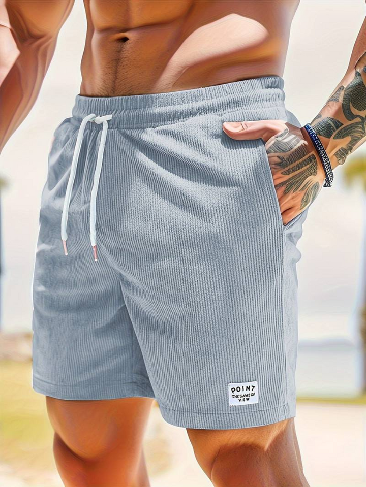 Model wearing versatile men's summer swim shorts for a casual beach look.