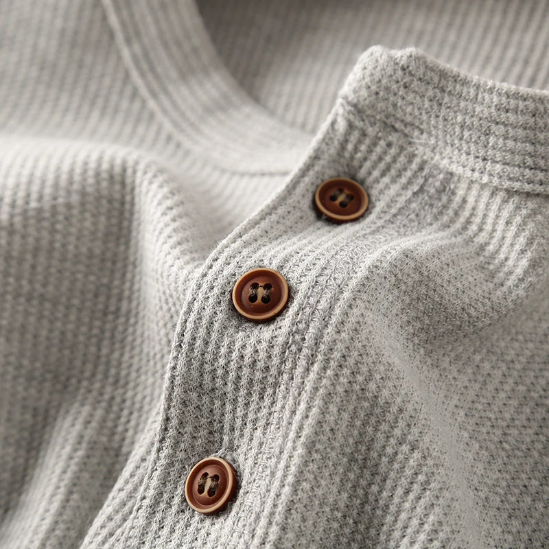 Model wearing a comfortable men's beige waffle knit henley shirt, versatile top