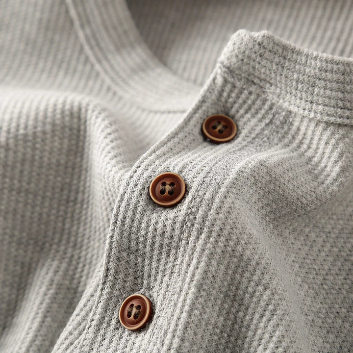 Model wearing a comfortable men's beige waffle knit henley shirt, versatile top